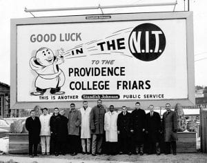 Friar fever is apparent as the players and coaches gather in front of a billboard prior to the 1961 NIT, the team’s third consecutive appearance in the tournament.