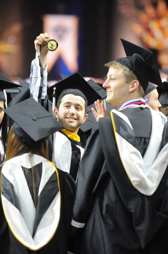 A graduate displays the centennial medallion that was worn by all graduates. 