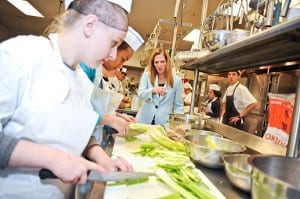 Dr. Sheila M. Harrity ’87 questions students preparing food in the kitchen of Worcester  Technical High School’s restaurant.