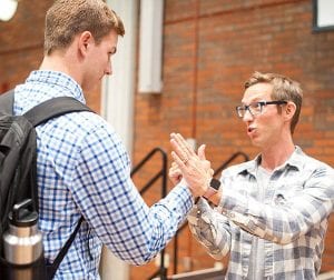 Joshua Davis, who referenced his venture into arm-wrestling in his convocation address, helps a student with a technique during the Q&A reception after the ceremony. 