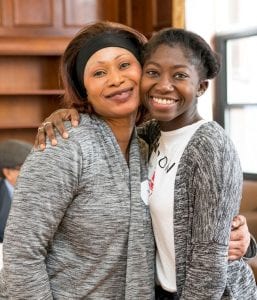 Amie Mbye ’18 gets a hug from her mother, Rose Lowe, at the 1G pinning ceremony for senior-class, first-generation students.