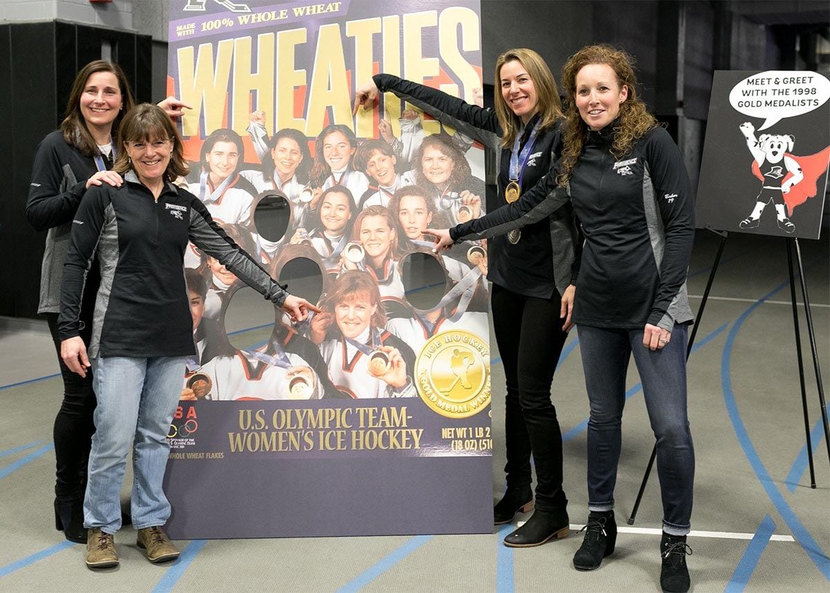 At FriarCon, Olympic teammates, from left, Vicki Movsessian '94, Lisa Brown-Miller '88, Sara DeCosta-Hayes '00, and Laurie Baker '00 point to their images on a Wheaties box.
