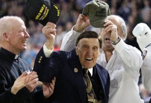 Ralph Paparella ’40 waves his cap to the Dunkin’ Donuts Center crowd, which stood to applaud his service in World War II. At left is PC President Rev. Brian J. Shanley, O.P. ’80.