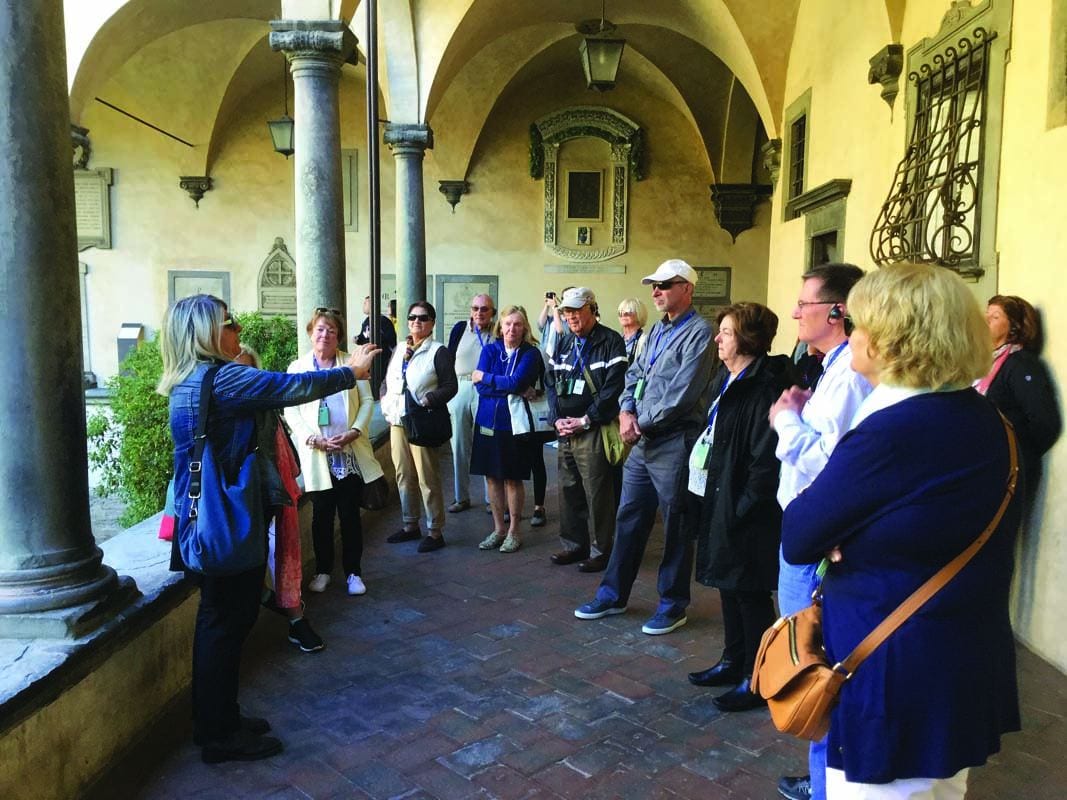 The PC group listens to a local guide outside the cloister of the Church of San Lorenzo in Florence, Italy, during a Dominican Destinations trip in 2017.