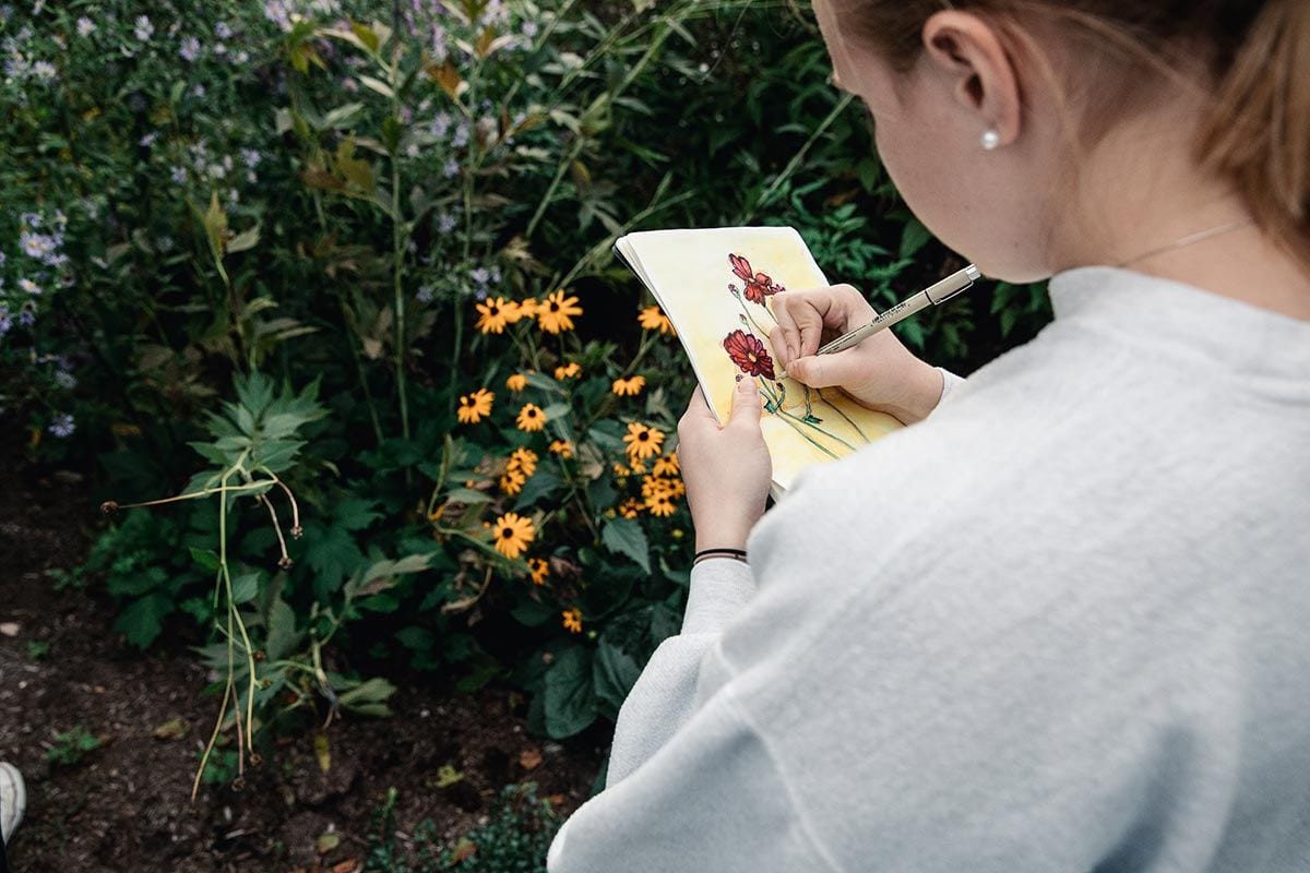Emily McQuaid '19 adds to her colorful sketch of flowers in the bioswale.