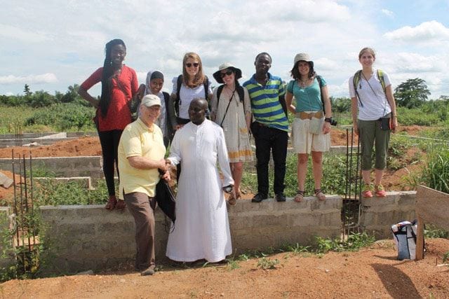 Dr. Stephen J. Mecca, front left, with students in Ghana. He is shaking hands with Rev. Bobby Benson '97G, who runs a home serving AIDS patients.