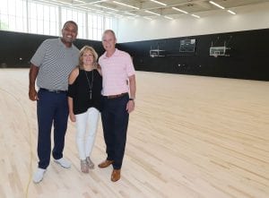 Karen and George Oliver join Ed Cooley, men's basketball coach, in the new basketball practice facility. One court is named for them.