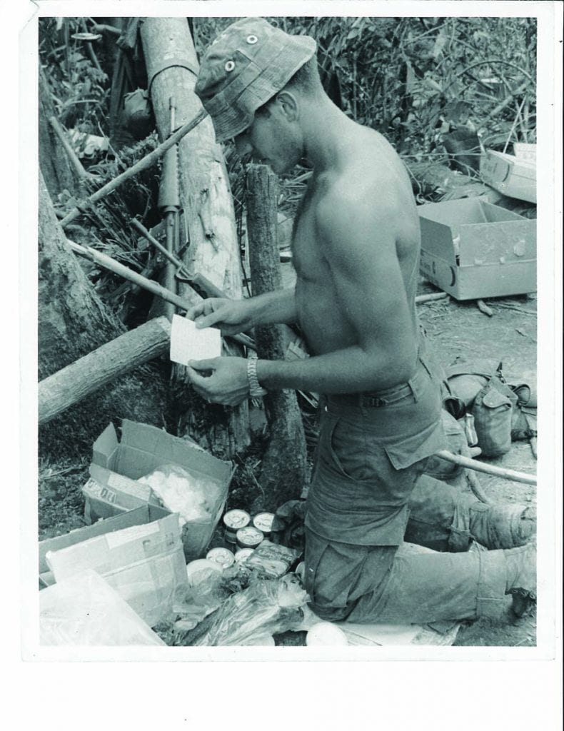 Gerry Dillon ’68 & ’74G unpacks a package from home while serving in Vietnam in 1970. Soldiers spent two to three months in the field. Every week, a helicopter would hover overhead to drop a supply of food, ammunition, and mail.