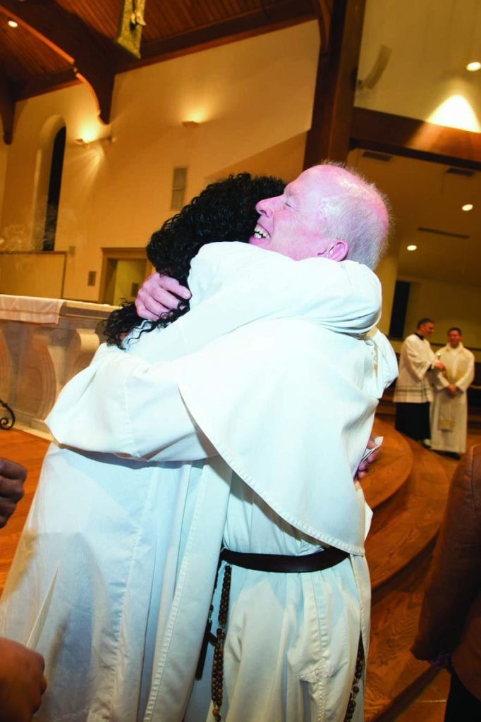 Sayou Cooper ’18 gets a congratulatory hug from College President Rev. Brian J. Shanley, O.P. ’80 after the RCIA Mass. Cooper, a double major in political science and history, worked in the president’s office after meeting Ann Machester-Molak ’75, assistant to the president and executive vice president, at a discussion group on diversity and inclusivity on campus. Manchester-Molak was her RCIA sponsor. Cooper spent her first five years at a refugee camp in Ghana before coming to the United States with her mother. She now is studying at Boston University for a master’s degree in urban affairs.