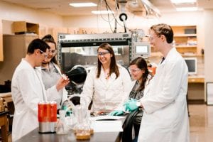 Dr. Maria A. Carroll, associate professor of chemistry, (center), in a chemistry lab with research students.