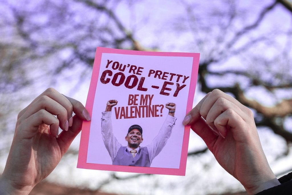 Hands hold a valentine that reads: "You're pretty Cool-ey. Be my Valentine?" with a picture of Coach Ed Cooley holding up his arms.