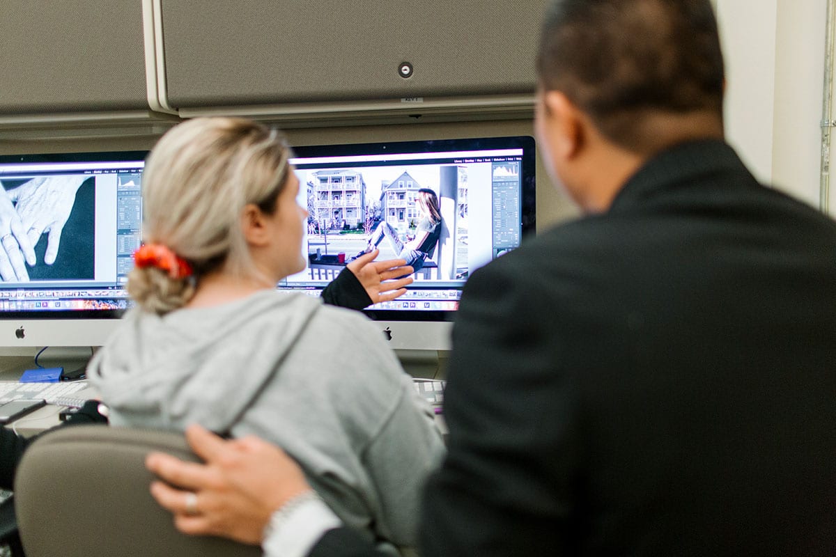 Eric Sung, associate professor of photography, helps a student edit a digital photo in the lab at Hunt-Cavanagh Hall.