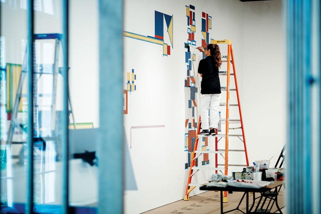 In the Reilly Gallery, Israeli artist Ronny Carny works on the mural "Colored Glass Destroys All Hate," which was commissioned as part of the group exhibition Tel Aviv: From the seafoam and clouds to the here and now. The exhibition was part of both the Beyond Bauhaus program and an annual exhibition series called Many Cities, One Providence, which features glimpses of art scenes from cities around the world so that students can draw connections between the arts and culture of Providence and places around the world. To date, the series has featured artists from Helsinki, Finland; Brockton, Mass.; Mexico City, Mexico; San Diego, Calif.; New Castile, Spain; Kansas City, Mo.; small cities of East Italy; and Tel Aviv, Israel.