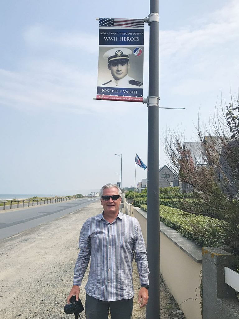 JIm Parks ’77 stands alongside the banner honoring the late Joseph P. Vaghi, Jr. ’42 in Normandy, France.