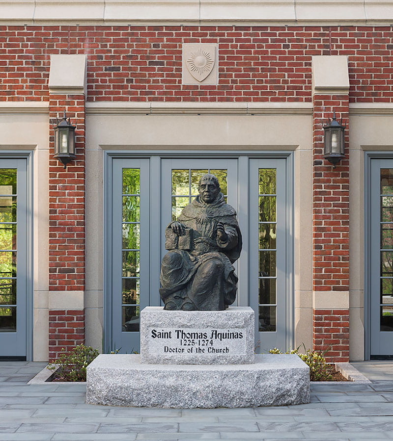 The life-size bronze statue of St. Thomas Aquinas, created by artist Sylvia Nicolas ’01Hon., stands outside the connector linking the Ruane Center for the Humanities to Phillips Memorial Library.