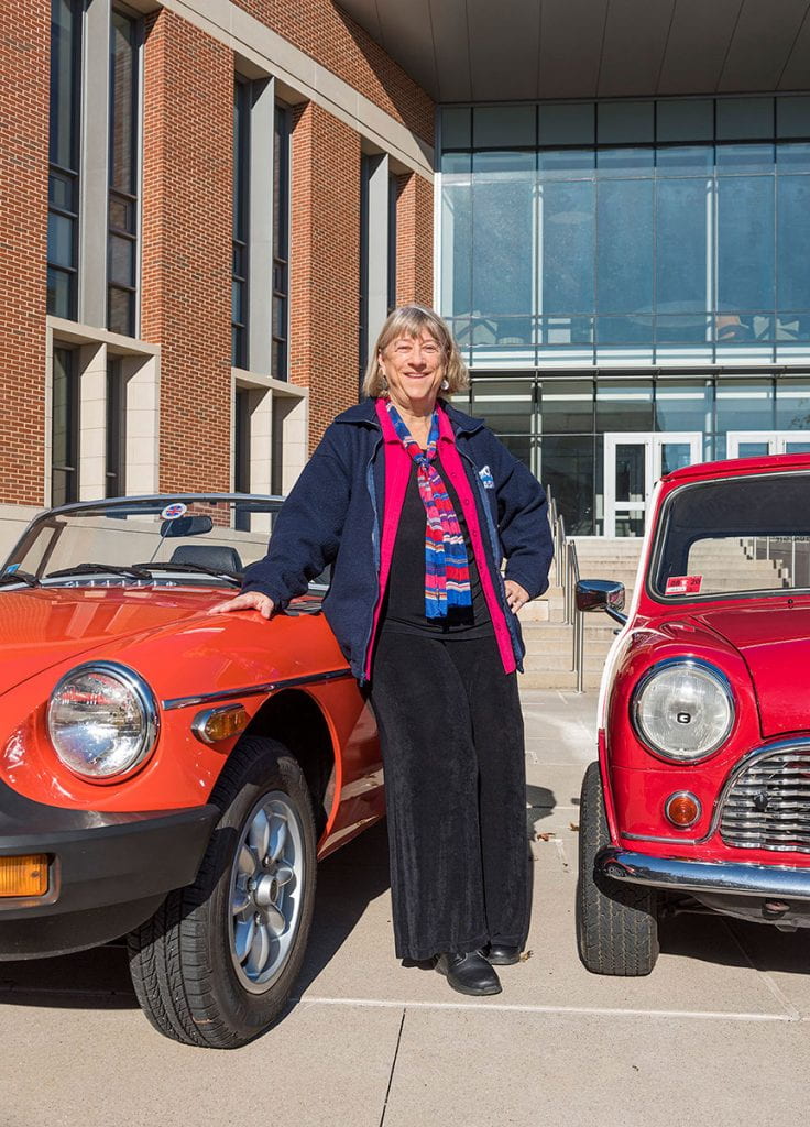 Faith Lamprey, a member of the full-time business faculty in accountancy, poses outside the School of Business with two of her cars, a 1980 MGB, left, and a 1967 Austin Mini.