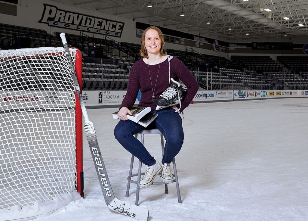 Clare Minnerath '20 sits on a stool on the ice at Schneider Arena with her hockey stick, skates, and books.