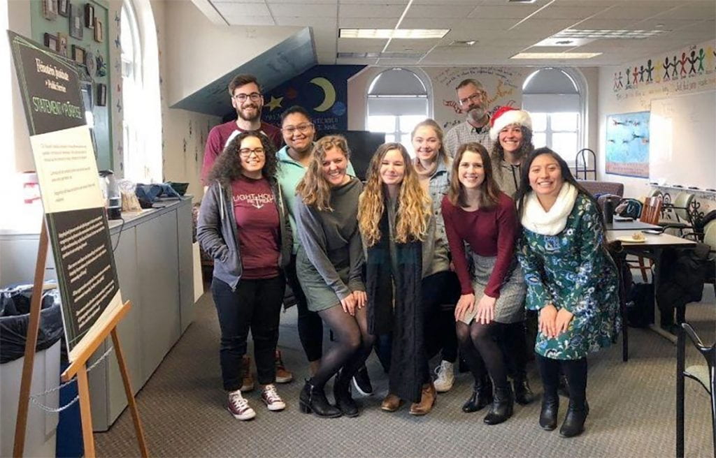 Katherine, front right, student peers, and instructors celebrate the final day of the public and community service studies practicum for the fall 2091 semester. With her are, front row from left, Ariel Davey ’20, Amelia Aaron ’20, Sara Murphy ’20, and Emily Locke ’20. At rear are William Bozion ’19, Perla Castillo Calderon ’20, Colleen Tuite ’20, Dr. Keith Morton, professor and department chair, and Rebecca Twitchell, instructor in public and community service studies.
