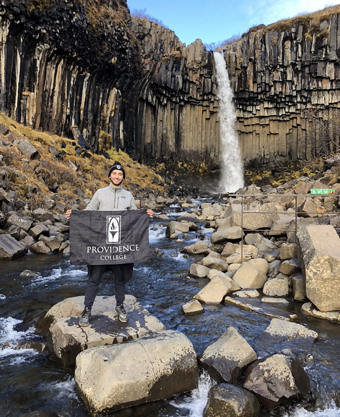 Nathan Perez ’20 proudly displays a College flag at the Svartifoss waterfall in Iceland while studying abroad last fall.