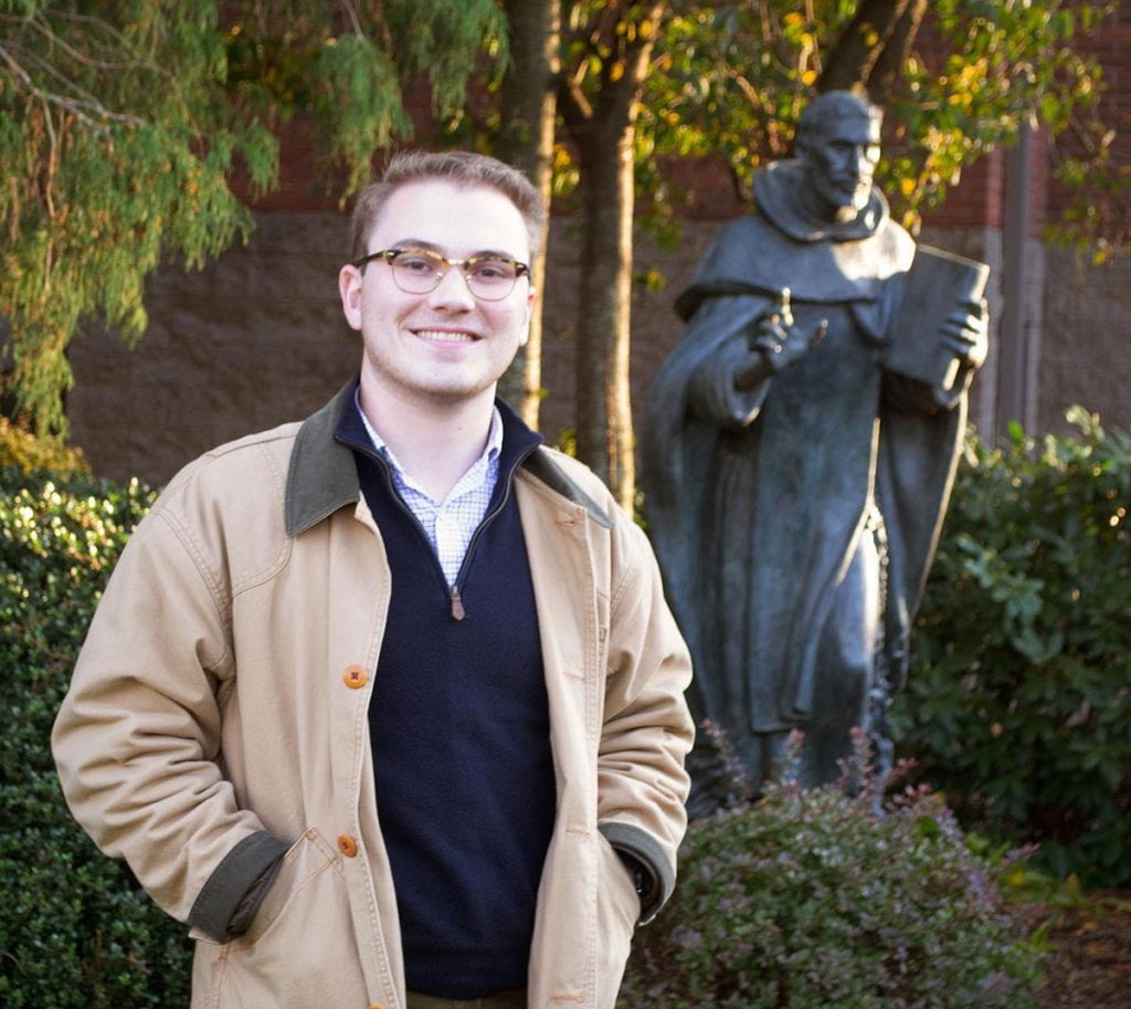 Sean Tobin ’20, in front of the statue of St. Dominic on campus, will enter the novitiate of the Dominican Order’s Eastern Province of St. Joseph in July in preparation for the priesthood.