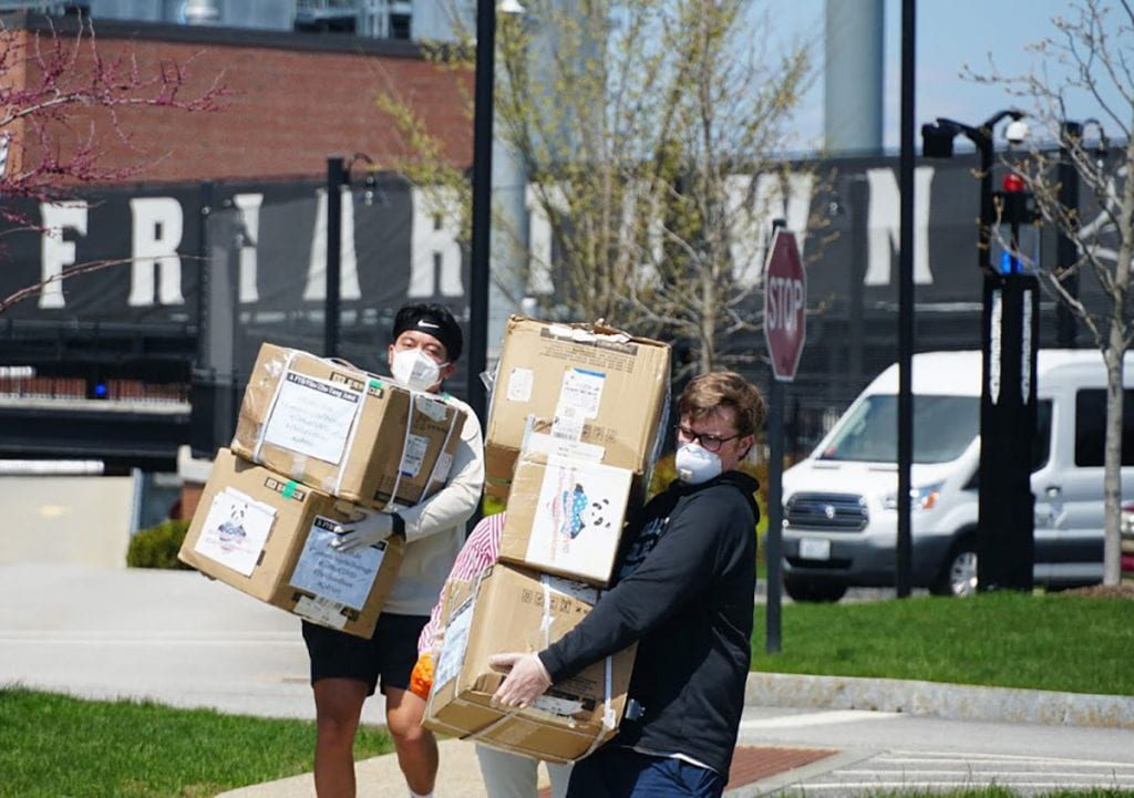 Kirk Esmero ’20, left, and Scott Bilotta ’20 carry boxes of masks on campus for distribution in the community.