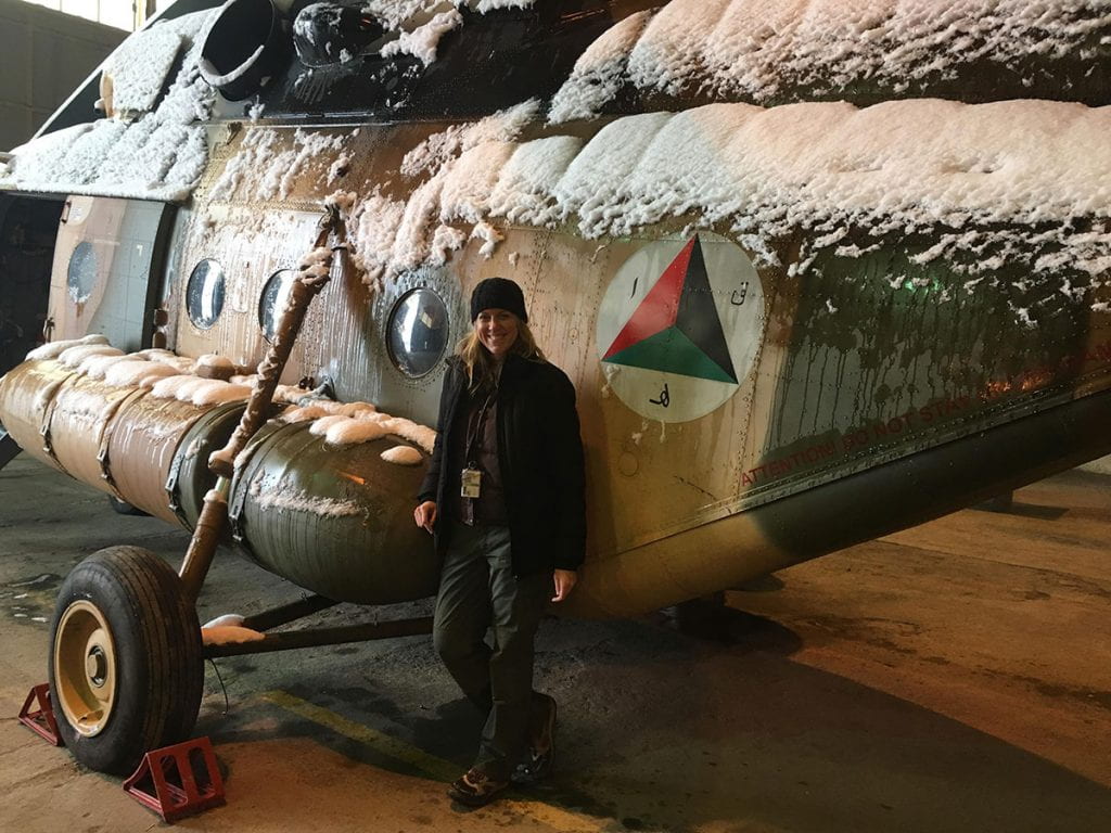 Laurie Hart ’03 leans against an MI-17 helicopter in Afghanistan, where she instructed MI-17 mechanics in English.