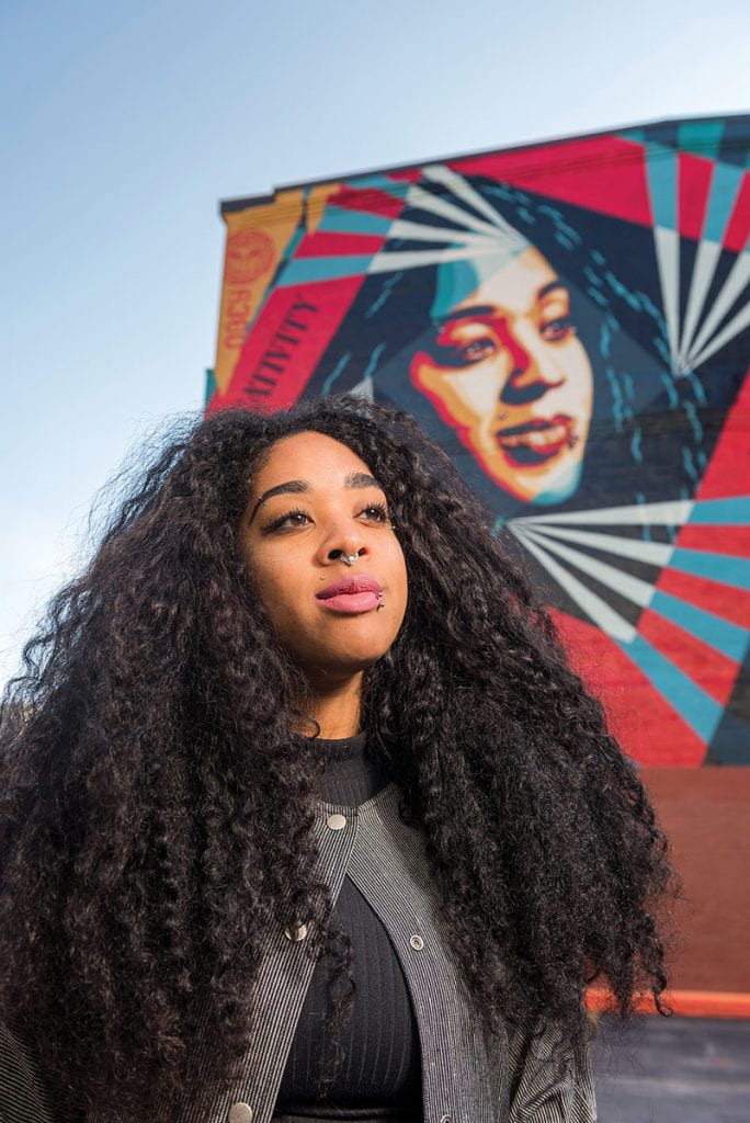 Anjel Newmann in front of the Shepard Fairey mural in Providence