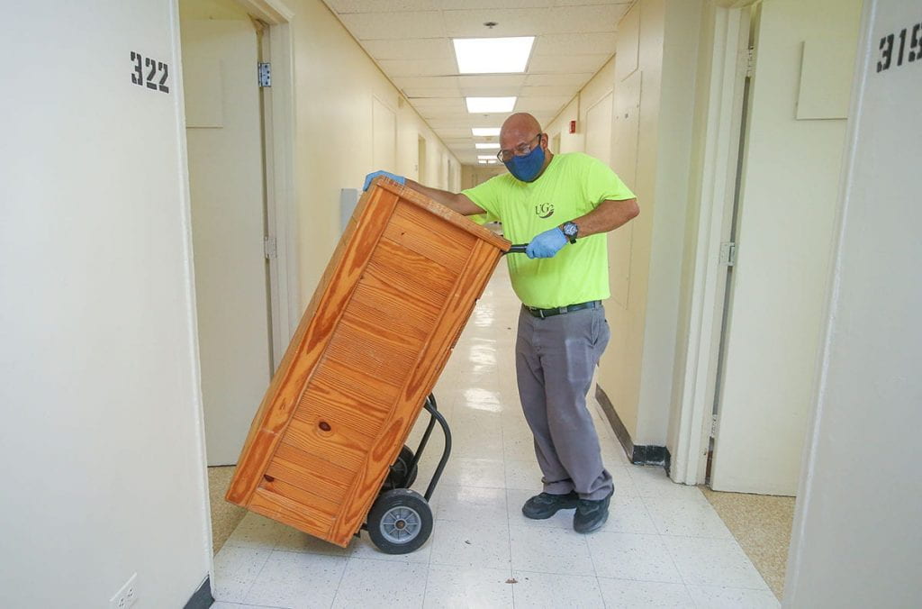 Furniture is removed from a room in Aquinas Hall to allow floors to be sterilized.