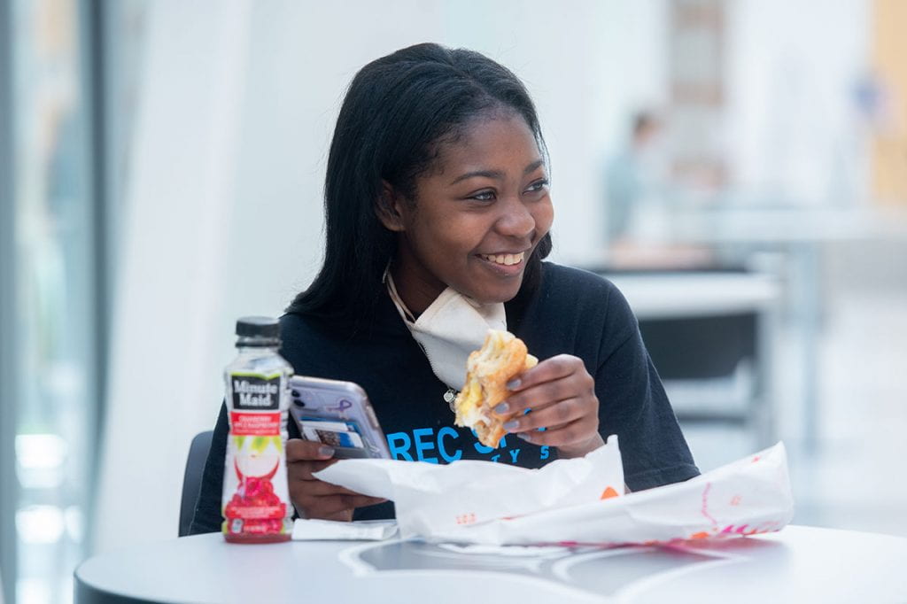 Yolanda Lewis '24 smiles during lunch in Raymond Dining Hall — one of few times students are able to lower their masks.
