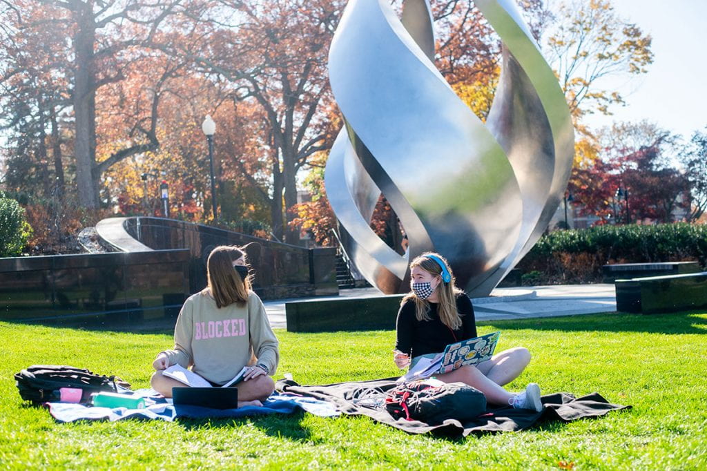 Near Calabria Plaza, Isabella Ganley '23, left, and Sinead Martin '23 take advantage of a warm afternoon to do their homework.