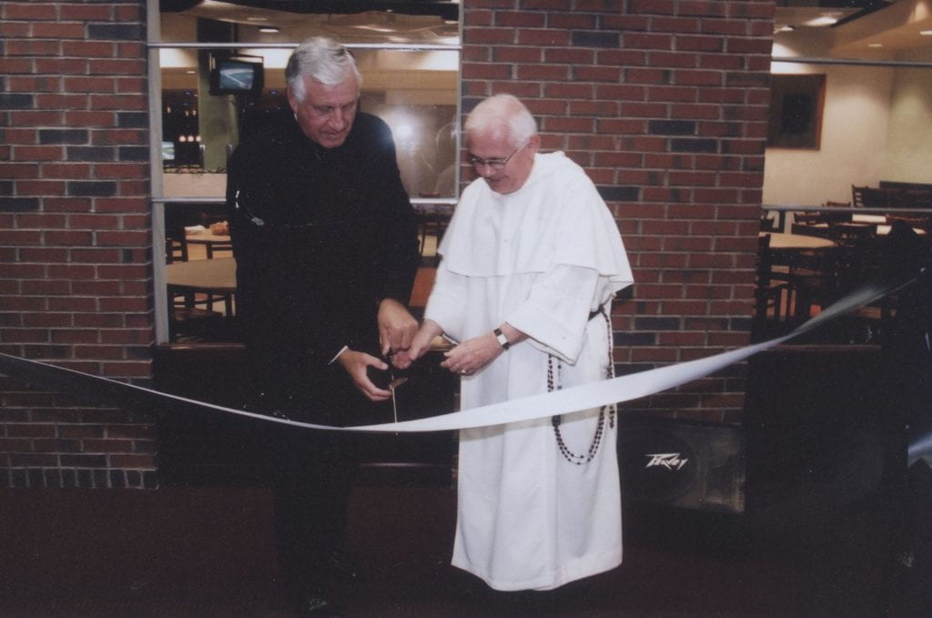 College President Rev. Philip A. Smith, O.P. ’63 cuts the ribbon as Rev. J. Stuart McPhail, O.P. ’61 assists at the opening of McPhail’s entertainment facility in Slavin Center in January 2002.