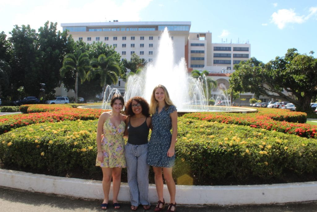 From left, Lauren Guerra ’19, Ann Gross Almonte ’19, and Madeleine Weil ’19, who all majored in health policy and management, stand outside a hospital in San Juan, Puerto Rico, in December 2018 during a trip to assist the research of their professor, Dr. Jessica Mulligan.