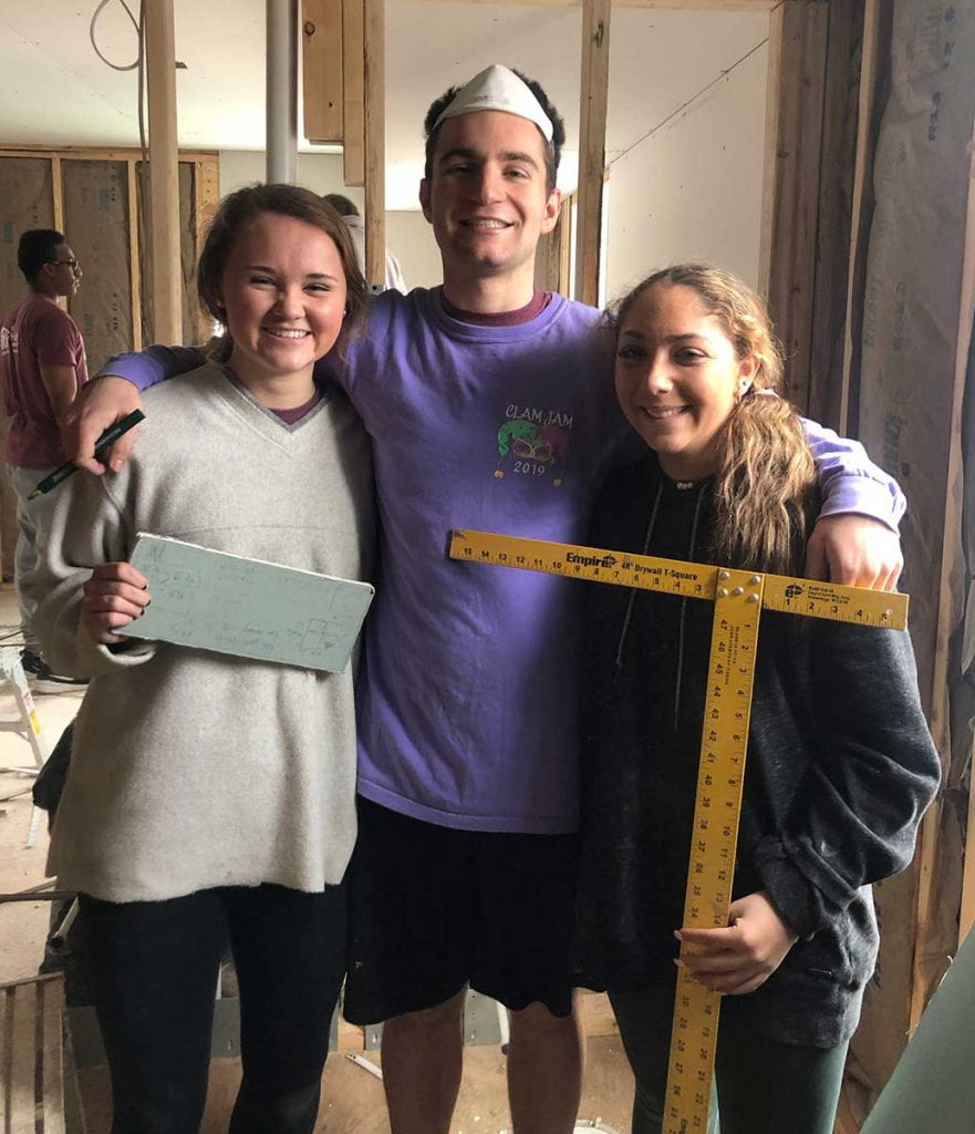 During a 2020 spring break trip to York, Pa., with Habitat for Humanity, Colby Agostino '22 poses for a photo while hanging drywall with Catherine Milner '21, left, and Bianca LaBella '23.