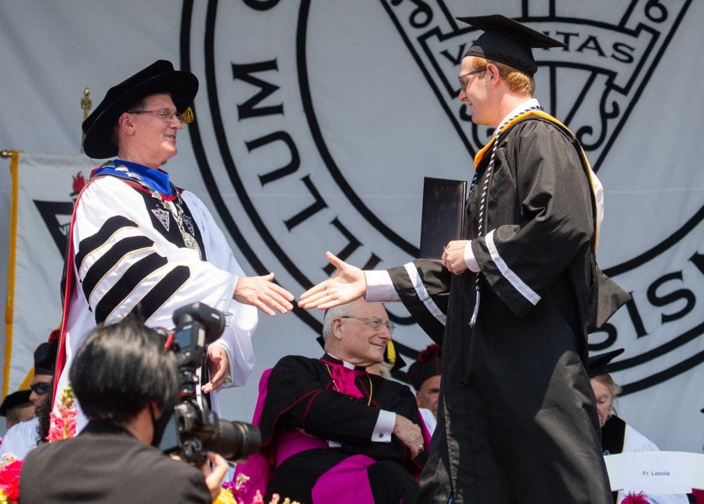 College President Rev. Kenneth Sicard congratulates a graduate at the undergraduate commencement