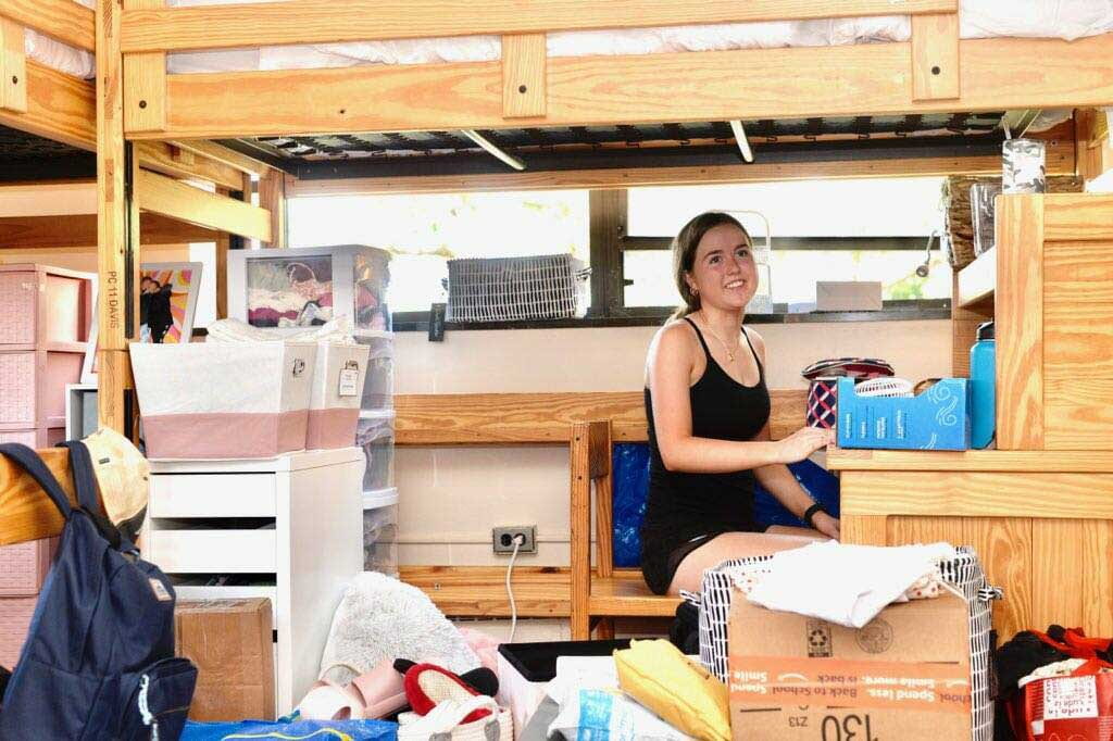 A student surrounded by belongings in her new room.