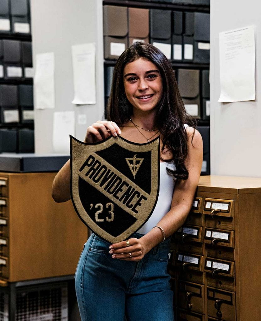 Isabella Corey '23 of Duxbury, Mass., holds the pennant that belonged to her great uncle, Rev. Matthew Leo Carolan O.P. '23, a member of the college's first graduating class.