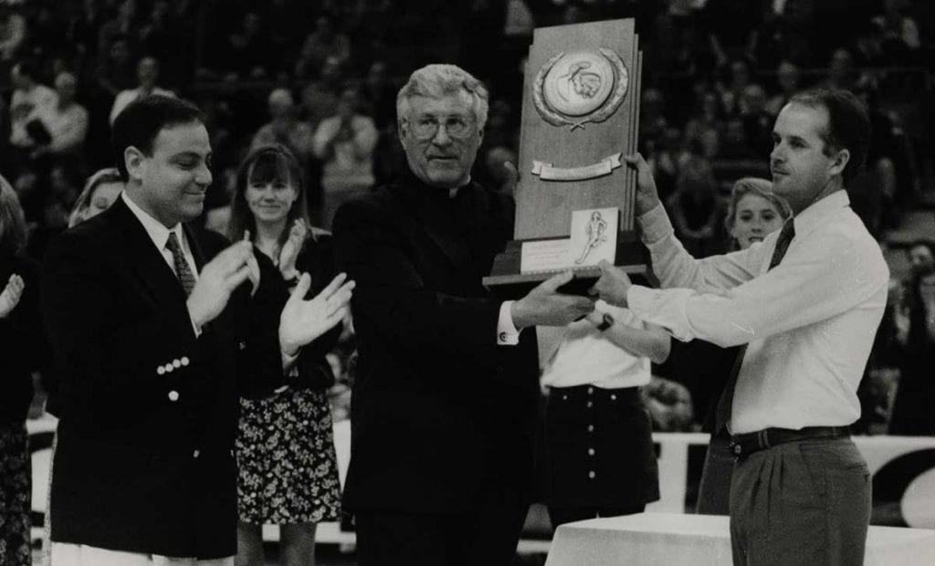 John Marinatto '79 celebrates the women's cross country NCAA Championship in 1995 with College President Rev. Philip A. Smith, O.P. '63, and coach Ray Treacy '82.