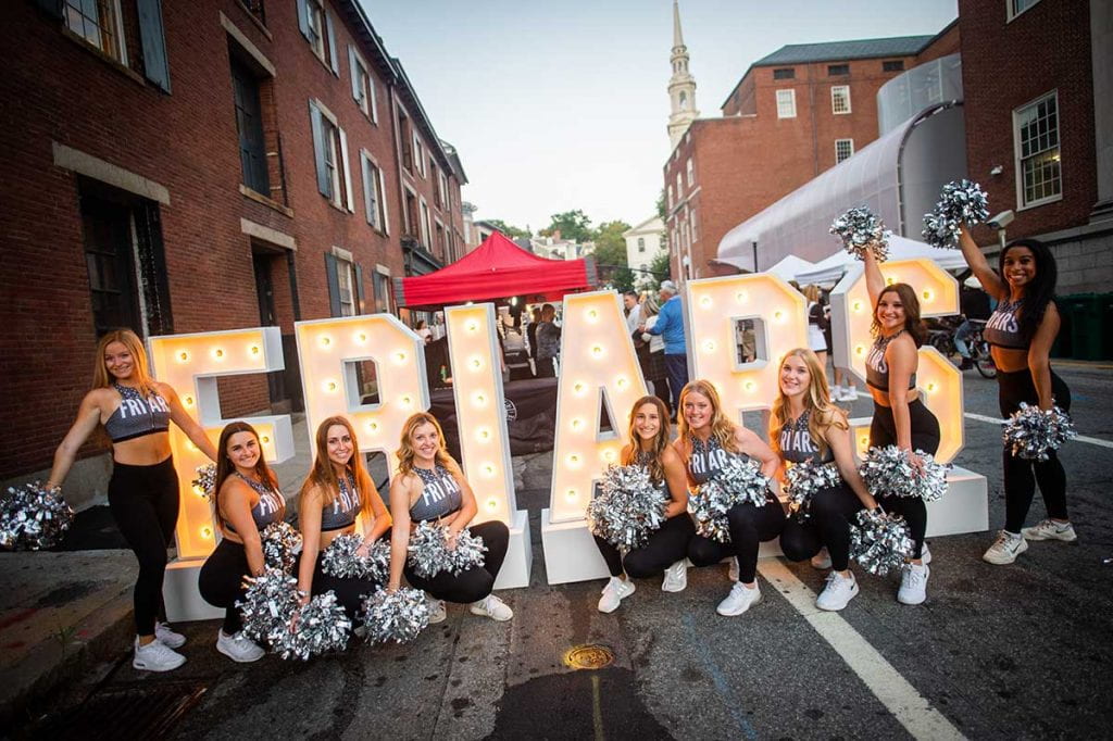 Providence College cheerleaders in front of the "Friars" sign at WaterFire