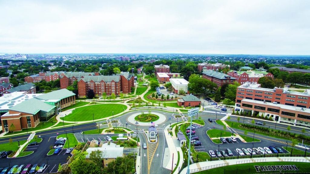 A transformed campus: The Arthur F. and Patricia Ryan Center for Business Studies, formerly Dore Hall, is at left, its parking lot replaced by a circular lawn. A portion of Raymond Hall is at right. Toward the top of the photo, above the traffic rotary, a green swath and walkways replace Huxley Avenue between Davis Hall, at left, and Accinno, Guzman, and Cunningham halls, at right.