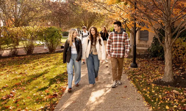 Group of students talking while walking around campus during the fall season