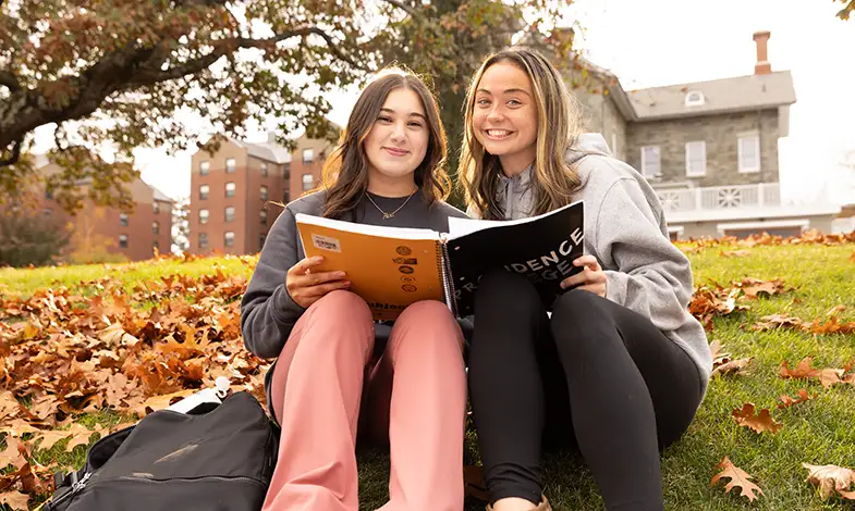 students sitting outside with a book