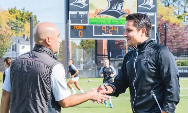 steve nap shaking hands with a student on an athletic field