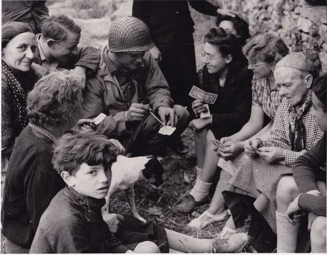 After D-Day, Navy Lt. Cmdr. Joseph Vaghi Jr. '42 spent 23 days in Normandy. Here he explains temporary currency to villagers. This photo was taken by an Army officer working for the Stars and Stripes newspaper. On a return to Normandy in 1994, Lt. Cmdr. Vaghi was reunited with two of the people pictured in this photo.