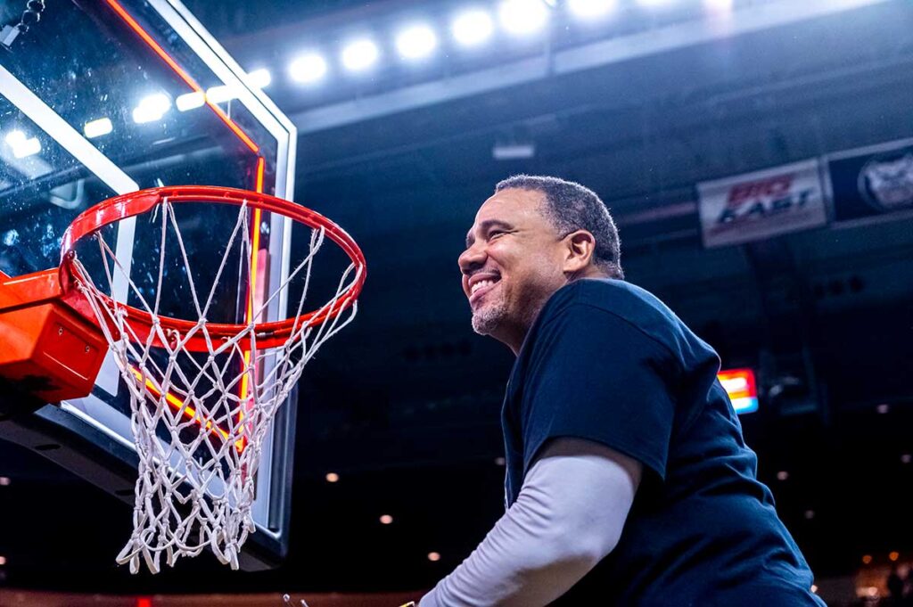 Men's basketball coach Ed Cooley prepares to cut down the net at the Dunkin' Donuts Center after the Frairs won their first regular season BIG EAST conference title in March 2022.