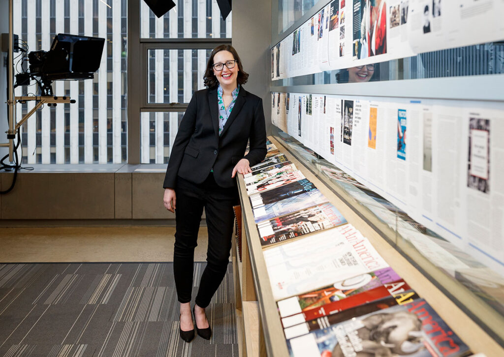 Kerry Weber '04 at America magazine offices in New York City. On the wall are proofs of the magazine issue under production.