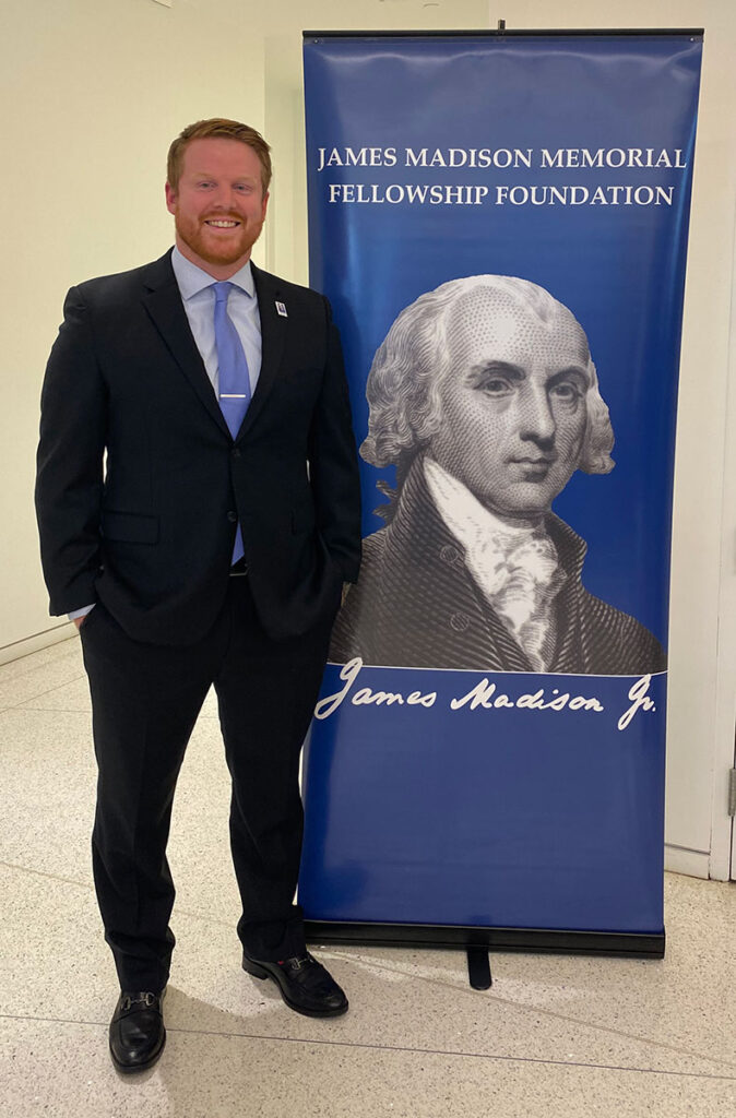 Michael McNamara '24G, a student in the graduate history program at Providence College, with a banner announcing the James Madison Memorial Fellowship Foundation.