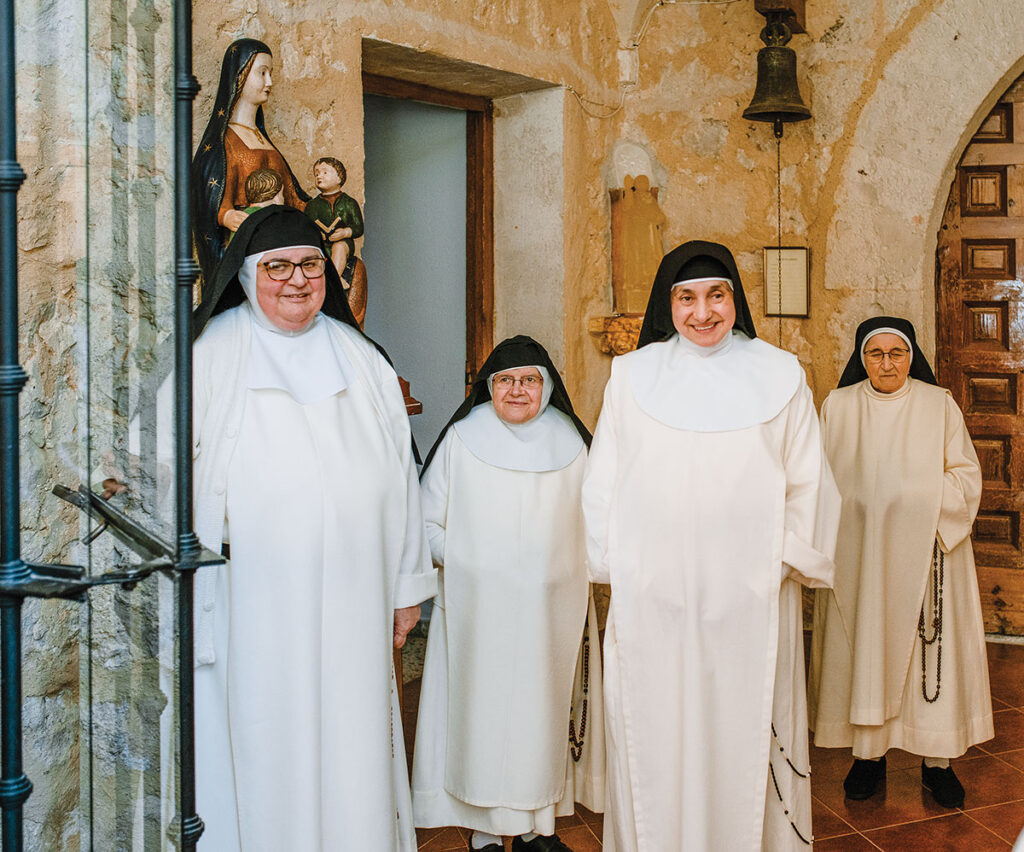Four cloistered nuns at the iron gate of the Monastery of Santo Domingo in Caleruega, Spain, wait to greet the PC pilgrims. They leave only for medical appointments or to care for aging parents.