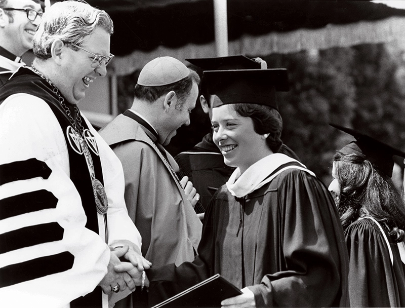 A graduating woman with College President Rev. Thomas Reginald Peterson, O.P. '51, '85Hon.