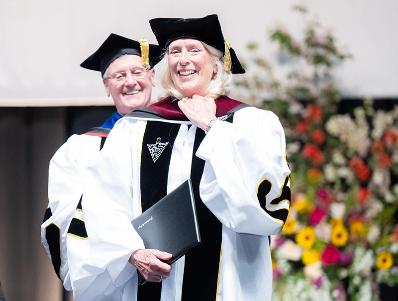 Ann Manchester-Molak '75, the college's first female executive vice president and a member of the first coeducational graduating class, adjusts her hood as College President Rev. Kenneth R. Sicard, O.P. '78, '82G presents her honorary degree.