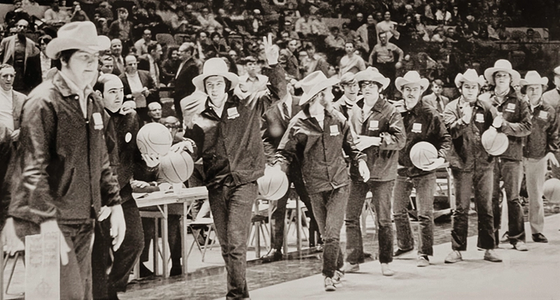 Students wearing cowboy hats and holding basketballs wave at the crowd at Madison Square Garden in New York City after dribbling there from Providence College.